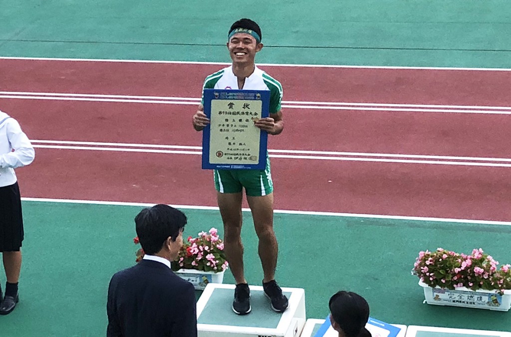 100mの賞状を手に表彰台に立つ熊井くん