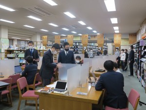 図書館で高1生徒の学習活動の様子を見学する受験生たち