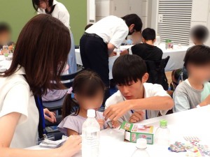 小学生の隣で組み立てを一緒に手伝います